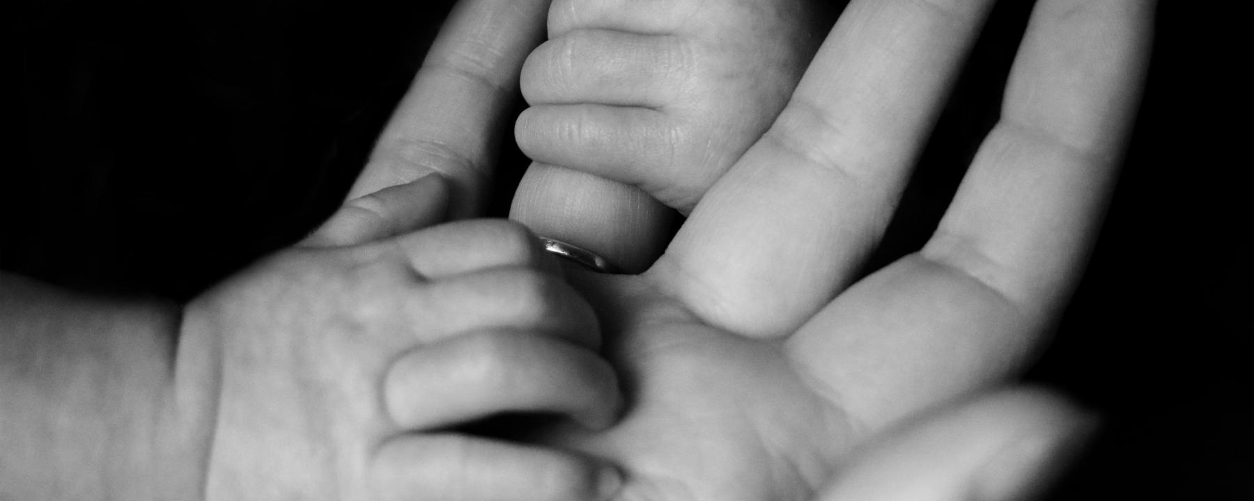 baby's hands holding mother's hand