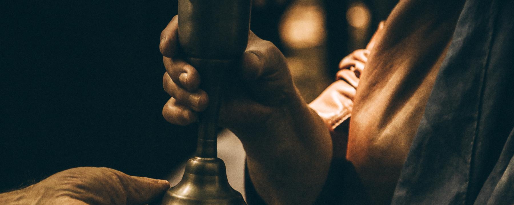 Two hands transferring a chalice from one to another, like Jesus with his disciples