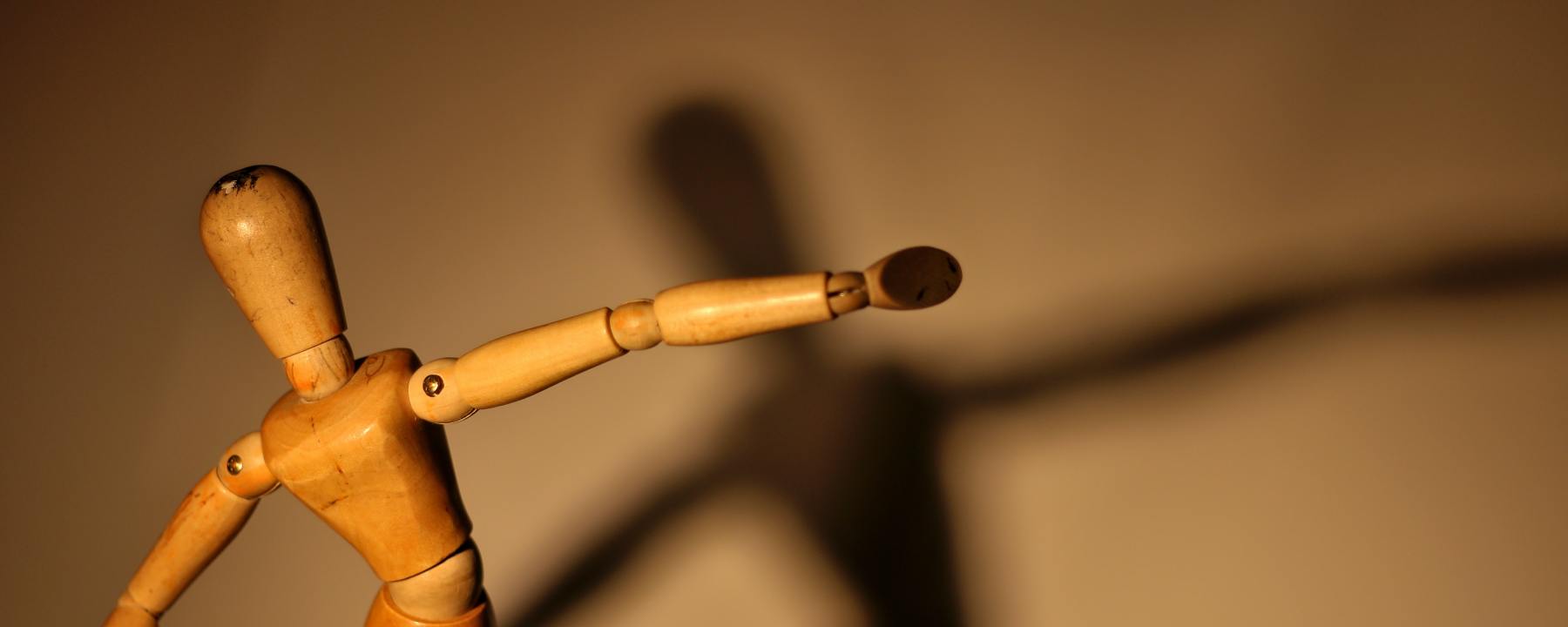 Wooden figure casting a graceful shadow
