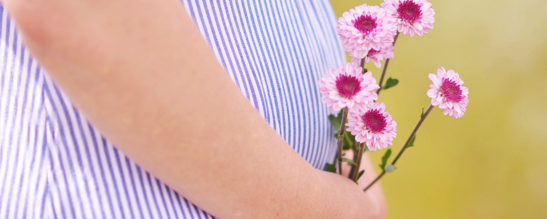 Close-up of pregnant women holding flowers over baby