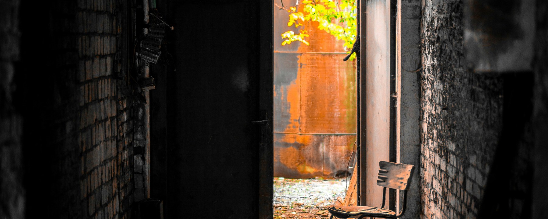 A dark enclosed alley with an open door at the end showing golden light