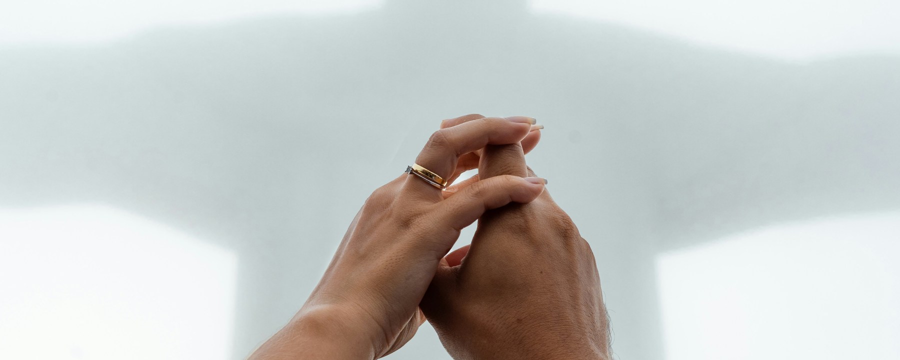 Two hands together in prayer with a misty image of Christ in the background